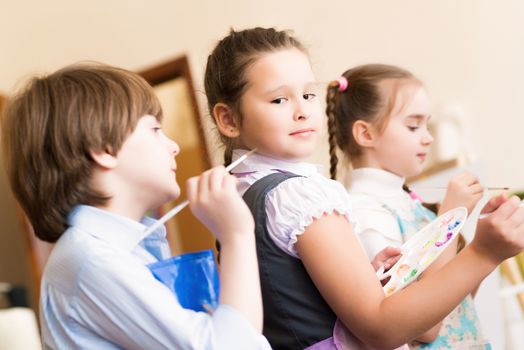 children paint easels for a lesson in the art school