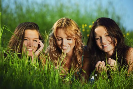 girlfriends lays on green grass and smile