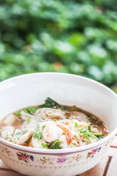 Thai spicy noodles soup with pork and shrimp on wood table