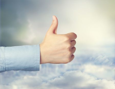 Person giving the thumbs up over cloudscape