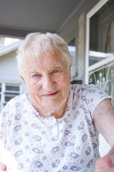 Portrait of happy senior lady in front of a house