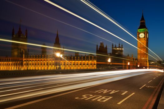 Light trails from London buses and vehicles with the Elizabeth Tower (Big Ben) of the Palace of Westminster in the background and the words Bus Lane in the foreground