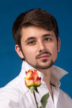 Man giving the red roses, on blue background.  Close up portrait.