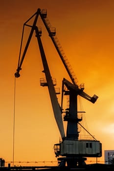 Silhouette of harbor crane at sunrise.