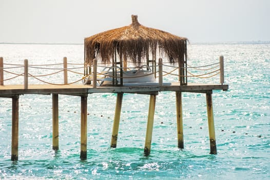 Pier with a bungalow on the sea background.