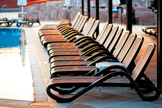 Several of sun loungers by the pool at sunrise