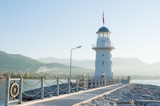 Landscape with a lighthouse in the harbor town of Alanya at dawn.