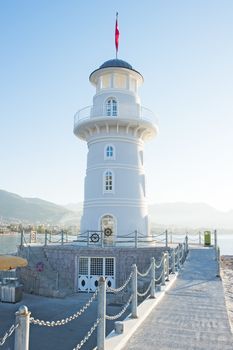 Landscape with a lighthouse in the harbor town of Alanya at dawn.