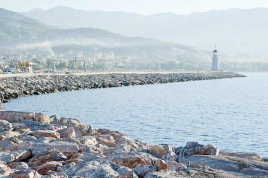 Landscape with a lighthouse in the harbor town of Alanya at dawn.