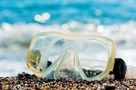 Diving mask lying on the sand by the sea.