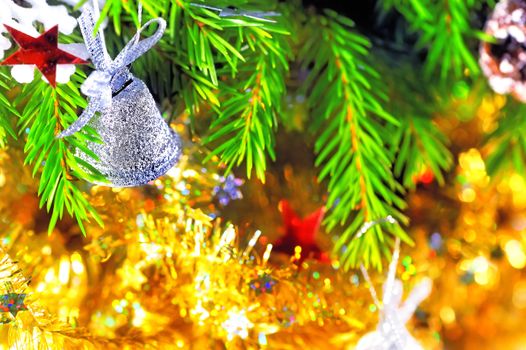 Silver bell hanging on the branch of a Christmas tree