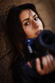 Attractive Mixed Race Young Adult Female Photographer Against Wall Holding Camera.