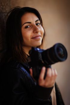 Attractive Mixed Race Young Adult Female Photographer Against Wall Holding Camera.