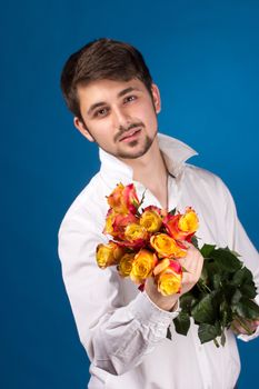 young man giving a red rose, on blue background