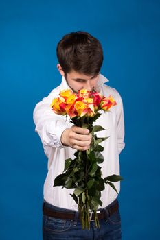 young man giving a red rose, on blue background