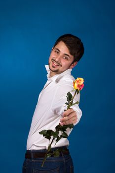 young man giving a red rose, on blue background