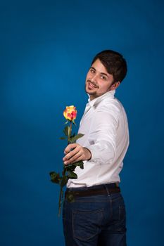 young man giving a red rose, on blue background