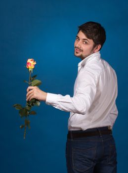 young man giving a red rose, on blue background