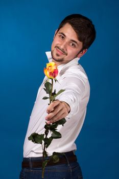 young man giving a red rose, on blue background