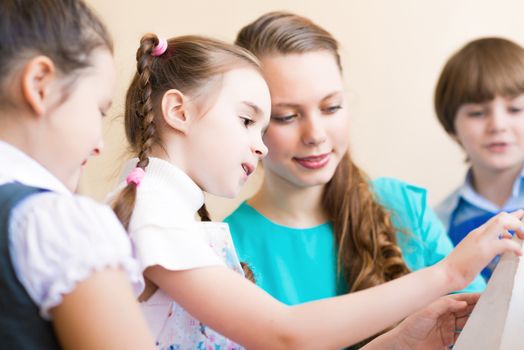 children with the teacher engaged in painting at an art school