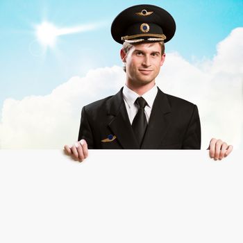 pilot in the form of holding an empty billboard on the background of sky with clouds, place for text