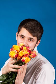 Man with bouquet of red roses. On blue background.