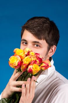 Man with bouquet of red roses. On blue background.