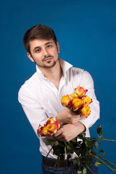 Man with bouquet of red roses. On blue background.