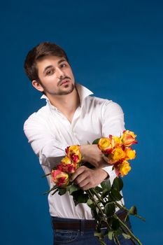 Man with bouquet of red roses. On blue background.