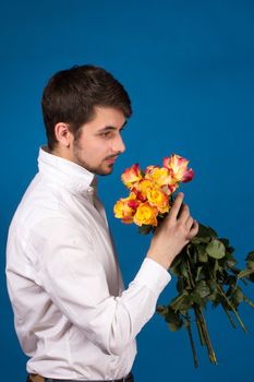 Man with bouquet of red roses. On blue background.