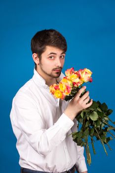 Man with bouquet of red roses. On blue background.
