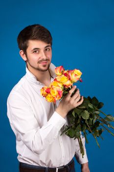 Man with bouquet of red roses. On blue background.