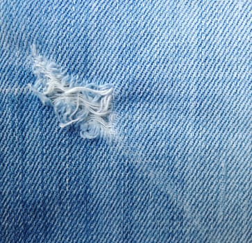 blue jean texture with a hole and threads showing

