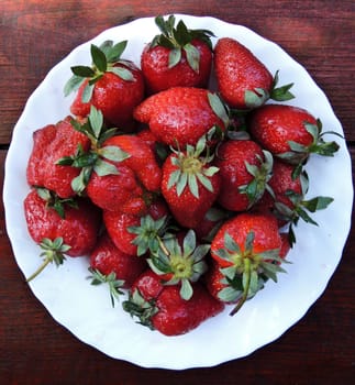 Strawberries on a plate on a wooden background