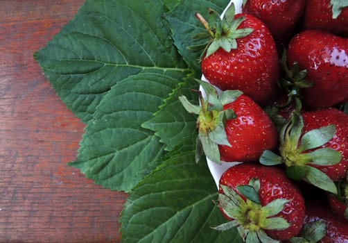 Strawberries on a plate on a wooden background