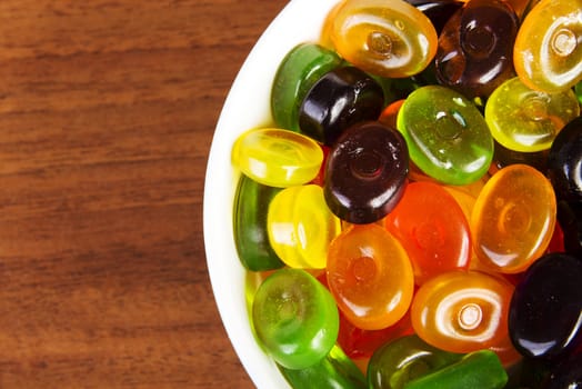 Candies in bowl on wooden table.