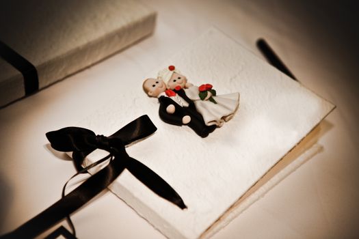 Guest book at a wedding decorated with a bride and groom and decorative bow