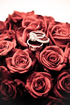 Wedding rings balanced on a bouquet of red roses, symbolic of everlasting love and commitment
