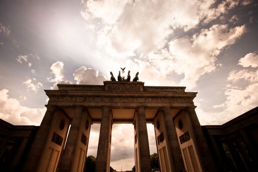 Brandenberg Gate in Berlin and the horses of the Quadriga silhouetted against a dramatic cloudy sky