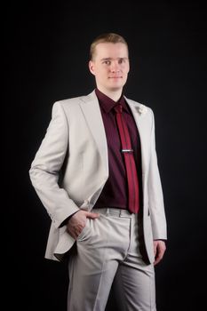 young attractive man in a light suit and tie on a black background