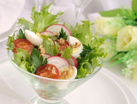 Salad of cherry tomatoes with quail egg and radish in the salad leaves