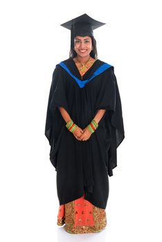Full body happy Indian university student in graduation gown and cap standing isolated on white background.