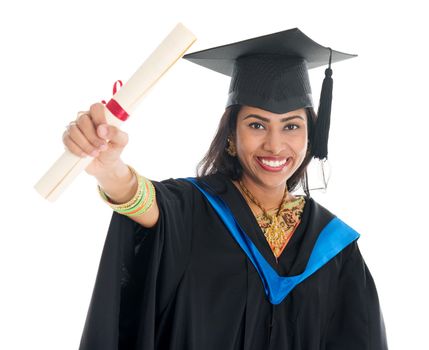 Happy Indian graduate student in graduation gown and cap showing her diploma certificate. Portrait of beautiful Asian female model standing isolated on white background.