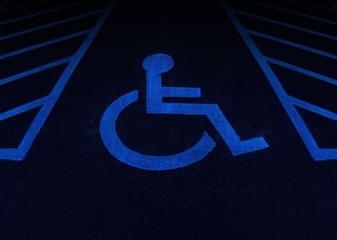 Handicapped and disabled symbol as a parking space with a wheelchair painted on asphalt as a health care and medical icon of reserved space for accessibility of the physically challenged.