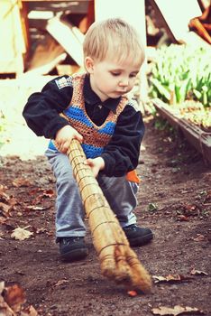 Little boy with a broom in hand cleaning your yard.