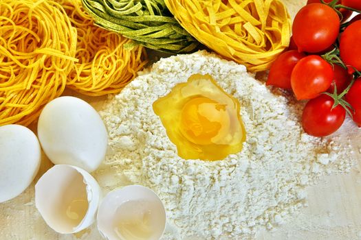 Ingredients for preparation of homemade egg pasta: flour, eggs, examples of egg pasta, tomatoes as a condiment.