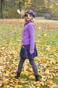 little girl plays with autumn leaves 