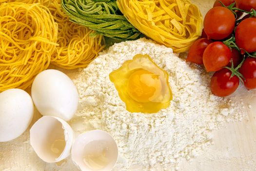 Ingredients for preparation of homemade egg pasta: flour, eggs, examples of egg pasta, tomatoes as a condiment.