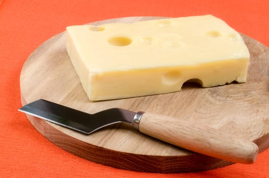 Cheese with a knife on a wooden board