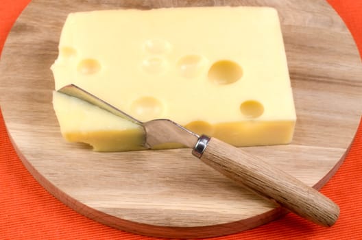 Cheese with a knife on a wooden board